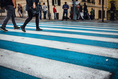 Low section of people walking on zebra crossing