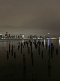 Panoramic view of sea and illuminated city against sky at night