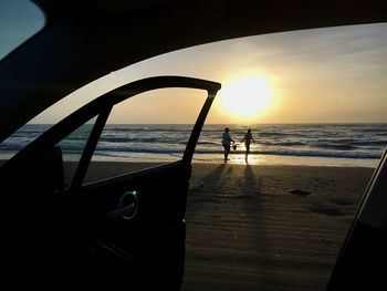 Silhouette people on beach against sky during sunset