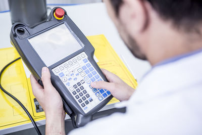 Close-up of man using control for industrial robot