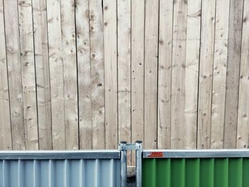 High angle view of metallic fence by wooden wall