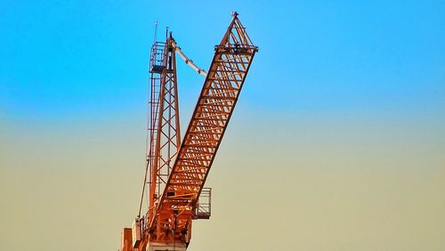 Low angle view of crane against clear blue sky