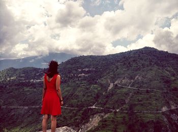 Rear view of man standing on mountain against sky