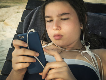 Girl listening to music while using phone on lounge chair