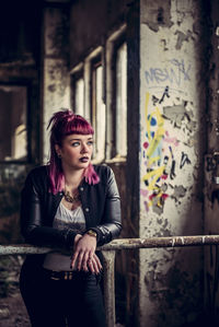 Thoughtful woman looking away while leaning on railing in abandoned building