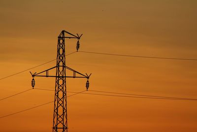 Low angle view of silhouette electricity pylon against sky during sunset