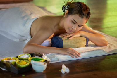 Topless young woman relaxing on bed at spa