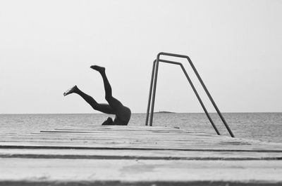 Low section of man diving into sea against clear sky