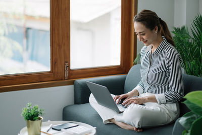 Businesswoman using laptop sitting on sofa