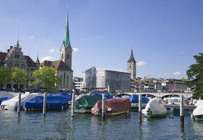 Sailboats in canal amidst buildings in city against sky
