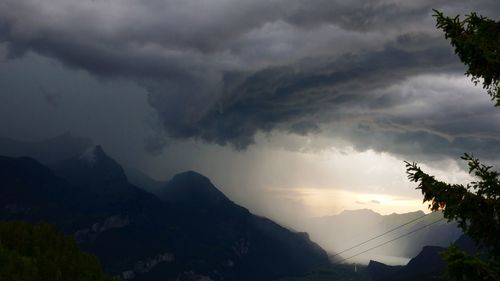 Scenic view of silhouette mountains against storm clouds
