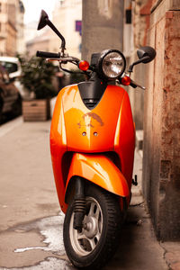 An orange moped stands on the street