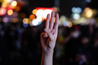 Midsection of person hand holding illuminated light at night