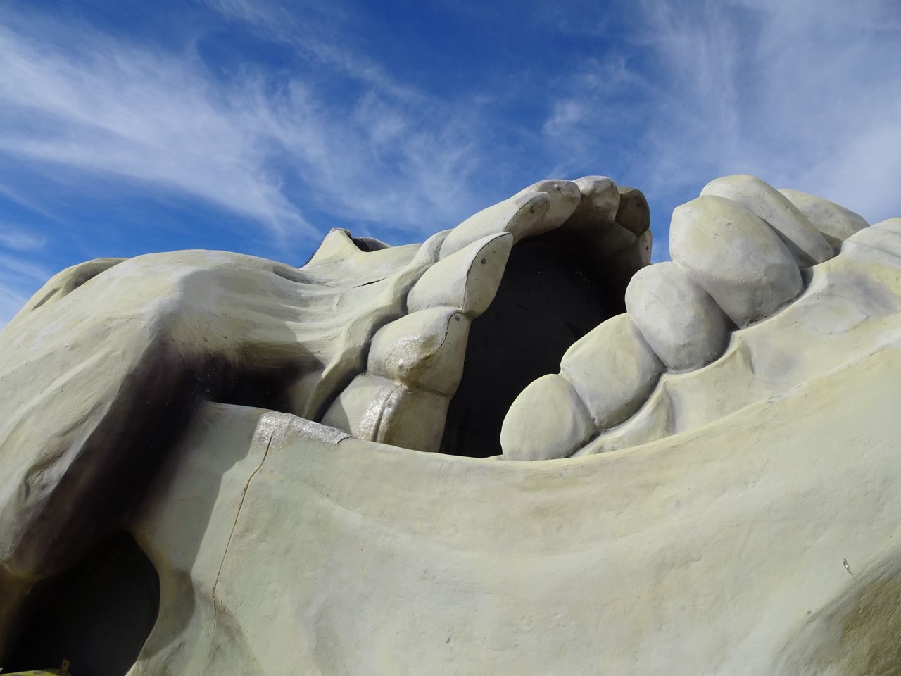 sky, low angle view, cloud - sky, cloud, day, nature, tranquility, outdoors, blue, no people, sunlight, cloudy, rock - object, tranquil scene, beauty in nature, mountain, art and craft, famous place, sculpture, scenics