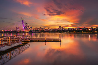 Illuminated bridge over river against sky during sunset