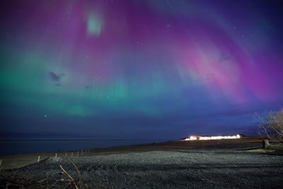 Scenic view of illuminated field against dramatic sky at night