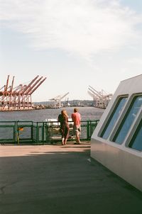 People on bridge against sky in city