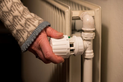 Female hand turning thermostatic valve on radiator