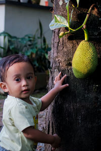 Portrait of cute baby girl on tree trunk