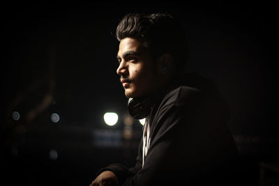 Portrait of young man looking away at night