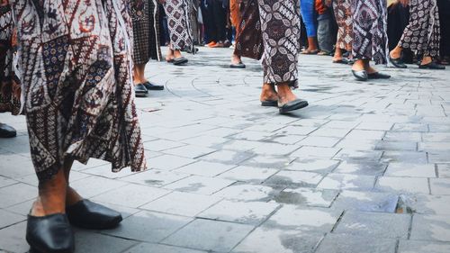 Low section of people wearing traditional clothing standing on footpath