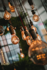 Low angle view of illuminated lighting equipment hanging in store