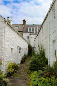 Footpath amidst buildings against sky