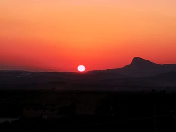 Scenic view of silhouette mountains against romantic sky at sunset