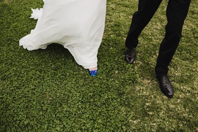 Low section of newlywed married couple walking on field