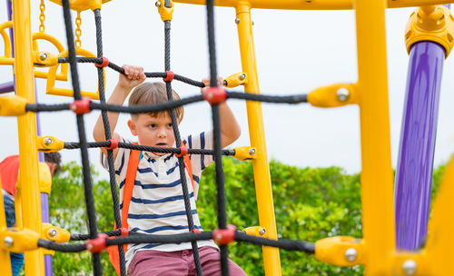 Cute boy climbing on jungle gym in playground