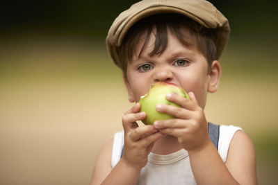 Close-up portrait of boy eating granny smith apple