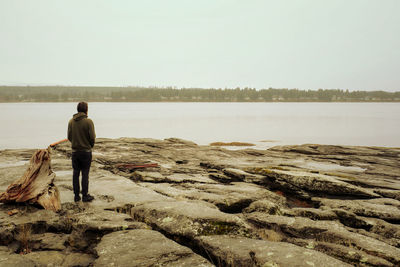 Rear view of woman walking on beach against clear sky