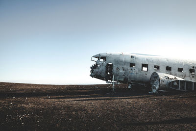 Abandoned airplane on field against clear sky