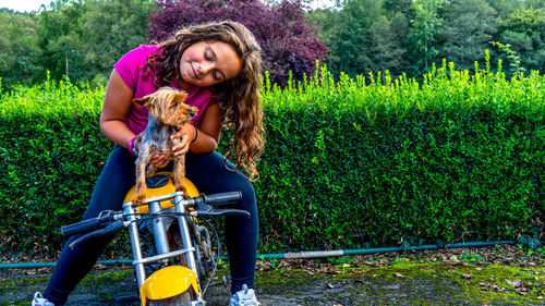 Girl with loose hair holding a puppy on top of a minibike