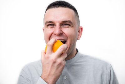 Portrait of man eating food against white background