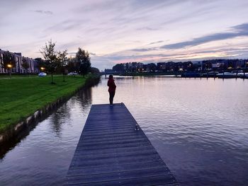 Rear view of man on pier against sky during sunset