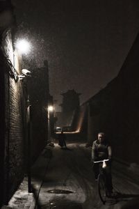 Rear view of man on illuminated street at night