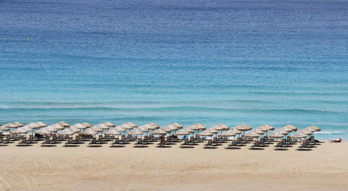 Deck chairs on beach against blue sky