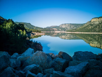 Scenic view of lake and rocks against blue sky