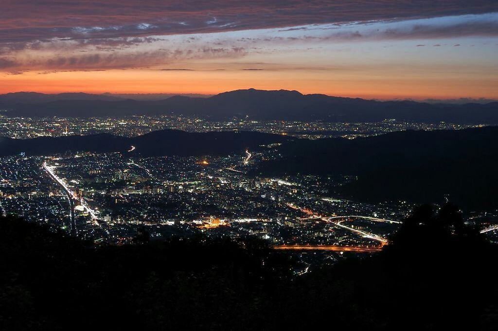 illuminated, cityscape, city, night, architecture, built structure, high angle view, building exterior, crowded, sky, aerial view, sunset, residential district, landscape, city life, dusk, mountain, residential building, outdoors, cloud - sky