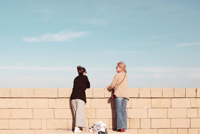 Woman with umbrella against wall
