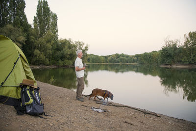 Senior man with dog camping at a lake