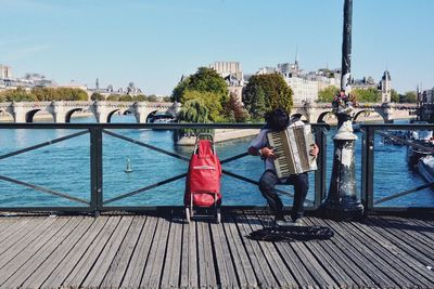 People on bridge over river against sky