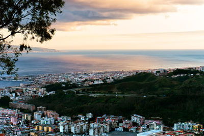 Aerial view of city by sea against sky