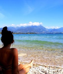 Rear view of woman looking at an italian lake blue waters against sky