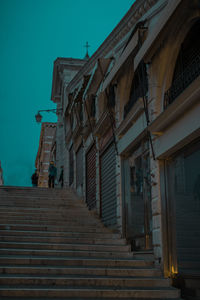 Low angle view of staircase amidst buildings against sky