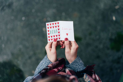 Midsection of woman holding greeting card outdoors