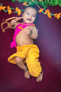 Cute indian boy dresses as lord rama with bow and flowers from top angle