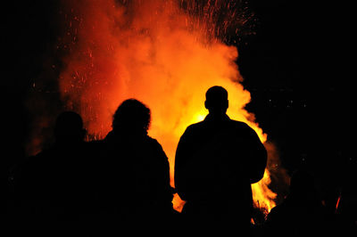 Silhouette people against fire at night