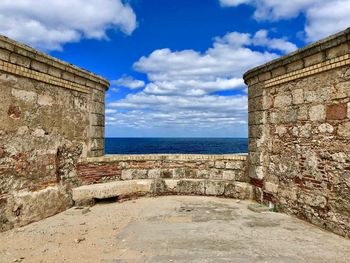 Stone wall by sea against sky